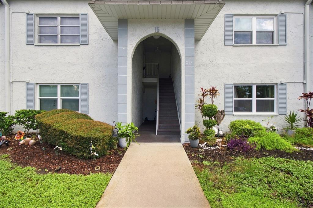 A concrete walkway leads to the arched entryway of a two-story apartment building — 217 S MCMULLEN BOOTH ROAD UNIT 179, CLEARWATER, FL