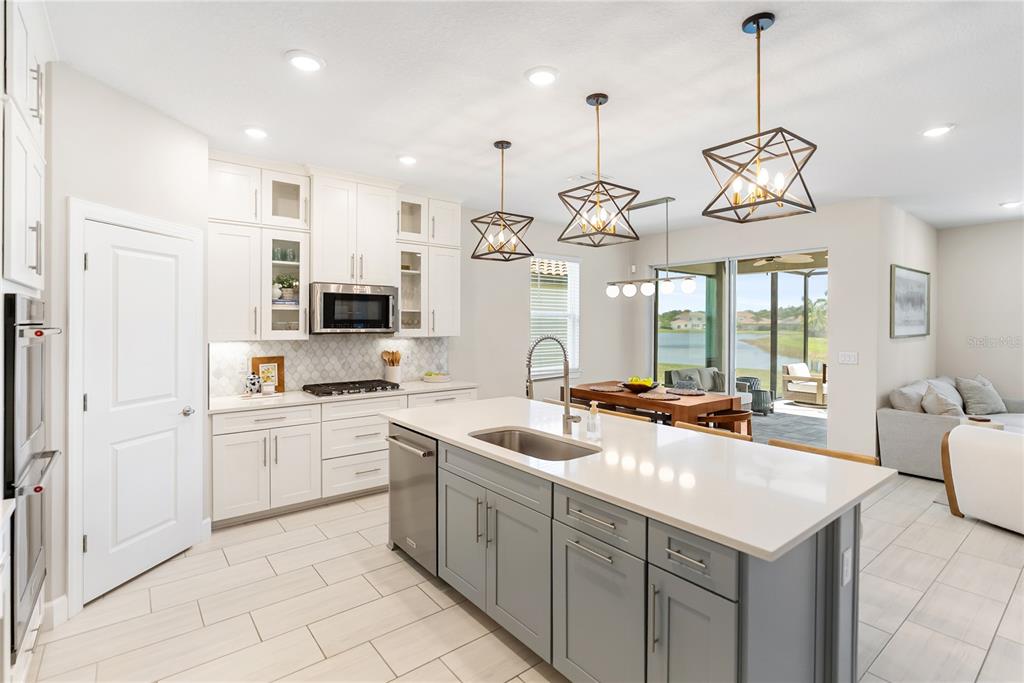 A modern kitchen features white upper cabinets, a gray island, and a view of a lake — 3312 BIG SKY WAY, BRADENTON, FL