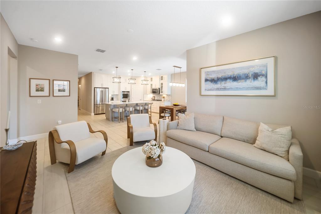 A living room with a sofa and two chairs opens into a kitchen with island seating — 3312 BIG SKY WAY, BRADENTON, FL
