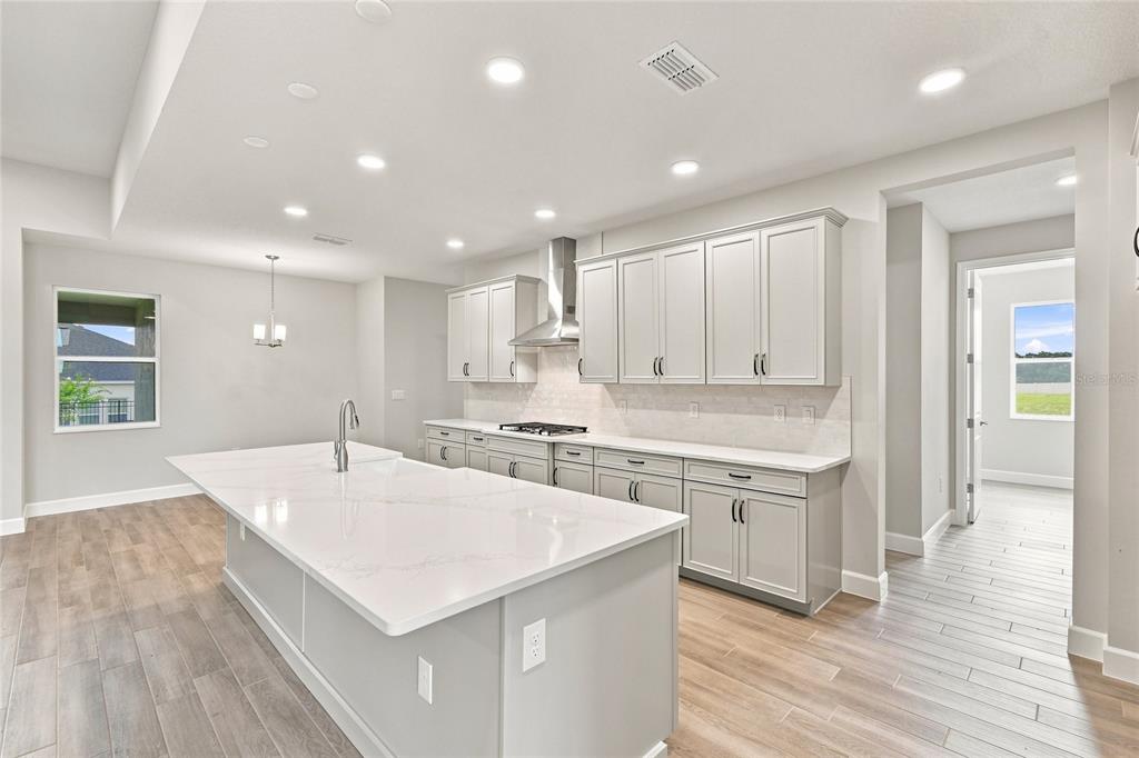 An open-concept kitchen and living area features light wood-look tile flooring and recessed lighting — 3177 WOLF LAKE AVENUE, APOPKA, FL