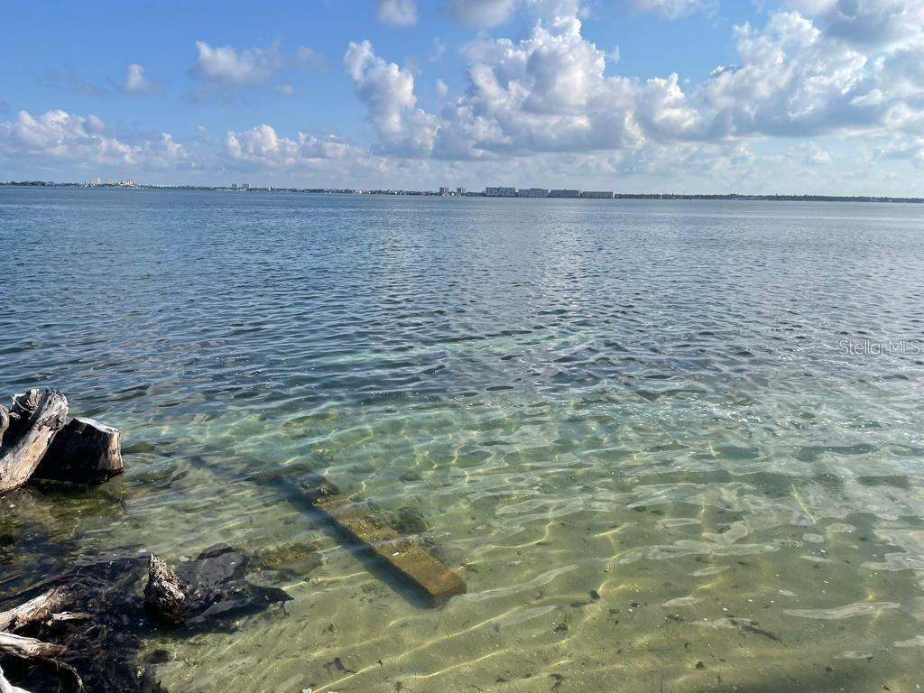 A vibrant sunset glows over a calm body of water with a distant shoreline silhouette — 6210 SUN BOULEVARD UNIT 202, ST PETERSBURG, FL