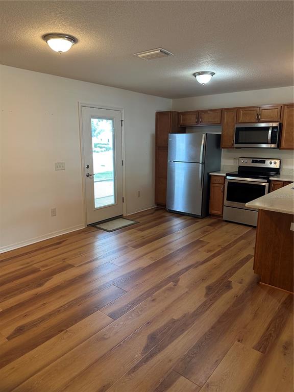 An open-concept kitchen and living area features light wood flooring, wooden cabinets, and white countertops — 716 TRUMAN AVENUE, LADY LAKE, FL