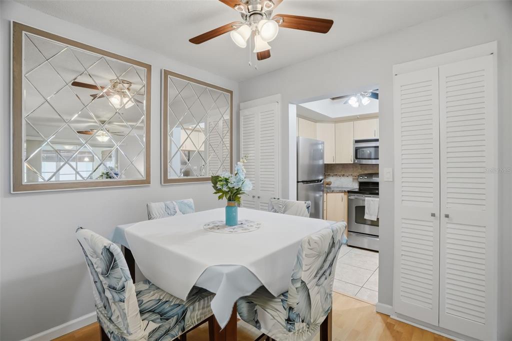 A living room features a ceiling fan, light wood floors, a television, and a breakfast bar — 5108 AMULET DRIVE UNIT 205, NEW PORT RICHEY, FL