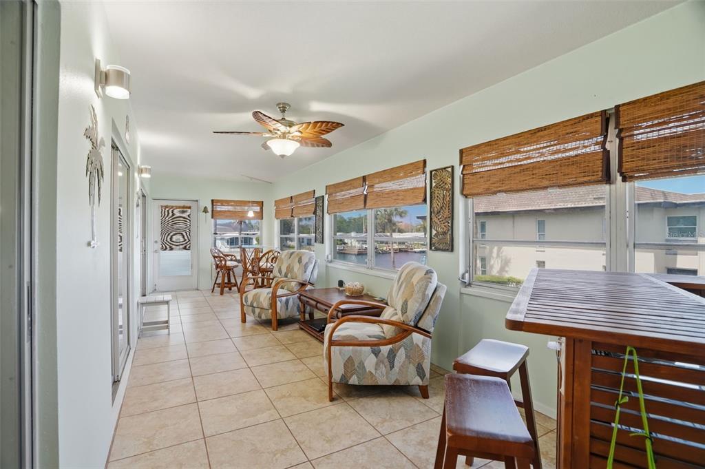 A dining area features a square table, floral chairs, wall mirrors, and a ceiling fan — 5108 AMULET DRIVE UNIT 205, NEW PORT RICHEY, FL