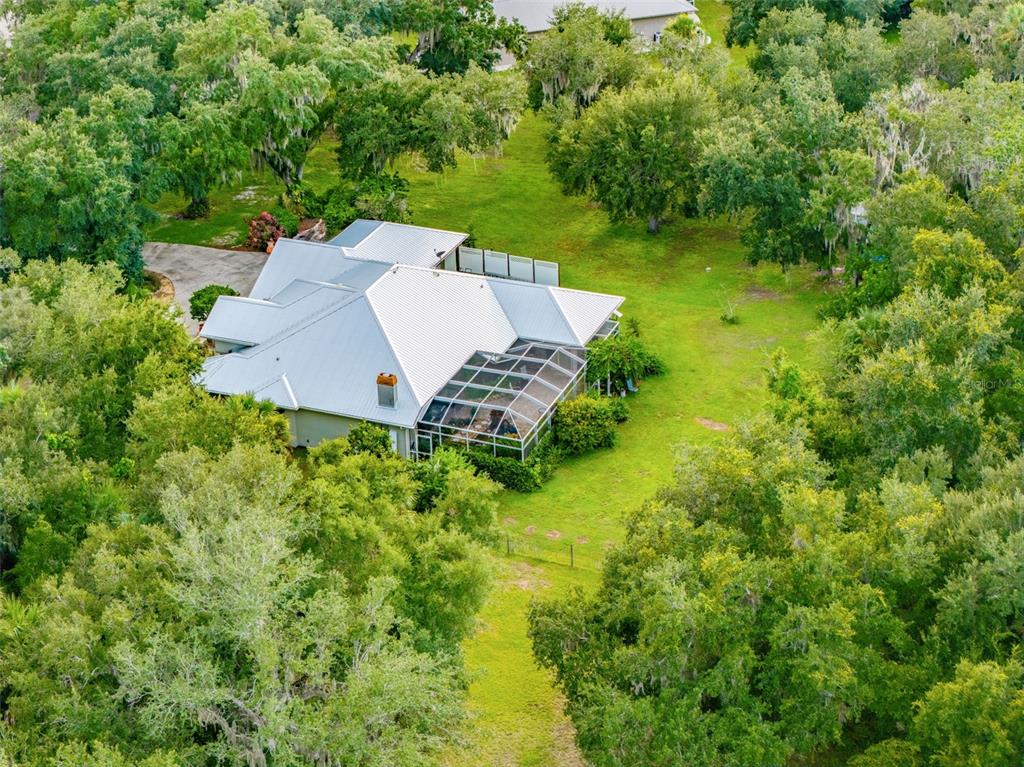 An aerial view of a house with a metal roof and a screened-in pool enclosure — 8596 SW RIVERSIDE DRIVE, ARCADIA, FL