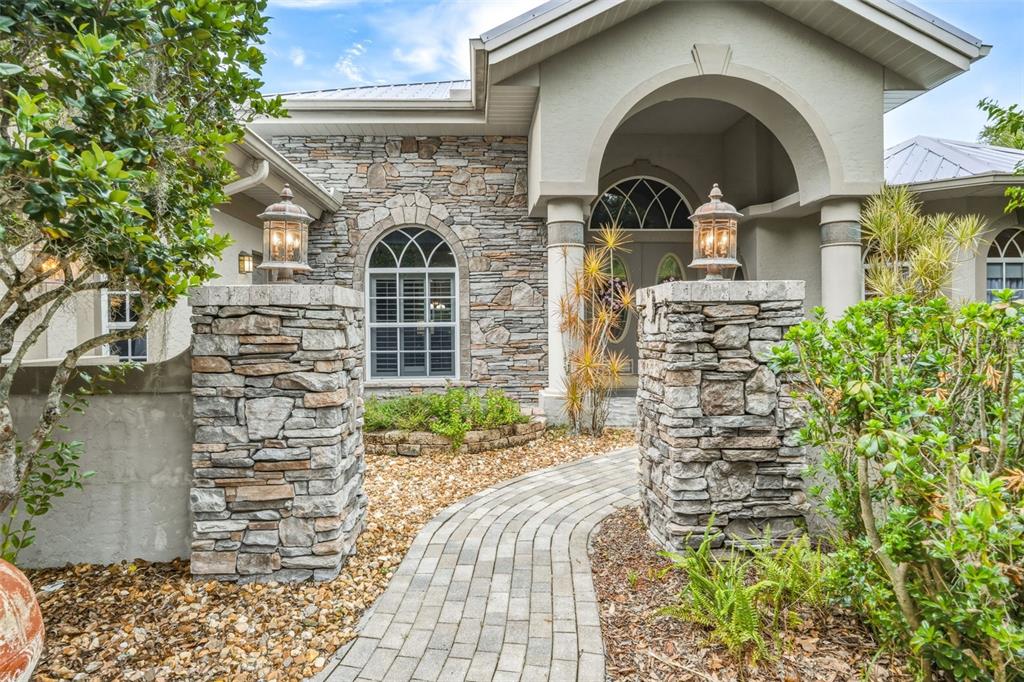 A stone-accented entryway features double doors with oval glass inserts, floral wreaths, and a statue — 8596 SW RIVERSIDE DRIVE, ARCADIA, FL