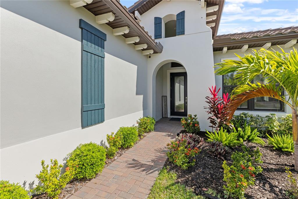 A paved walkway leads to the arched front entrance of a white stucco house — 2121 6TH STREET E, PALMETTO, FL