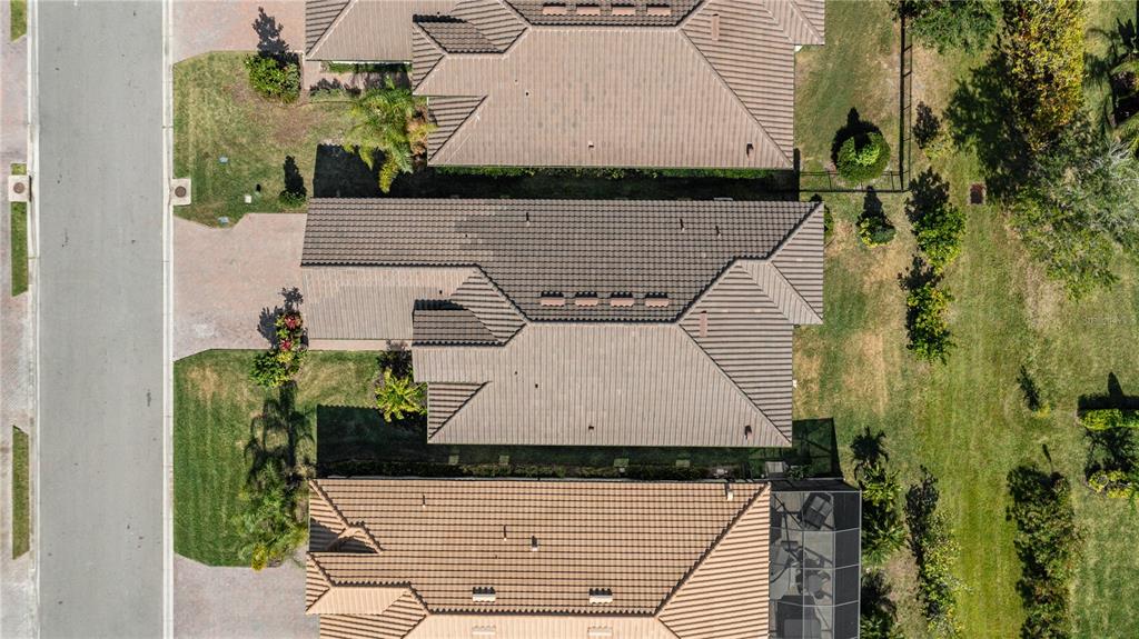 An aerial view shows three suburban houses with tiled roofs and driveways along a street — 2121 6TH STREET E, PALMETTO, FL