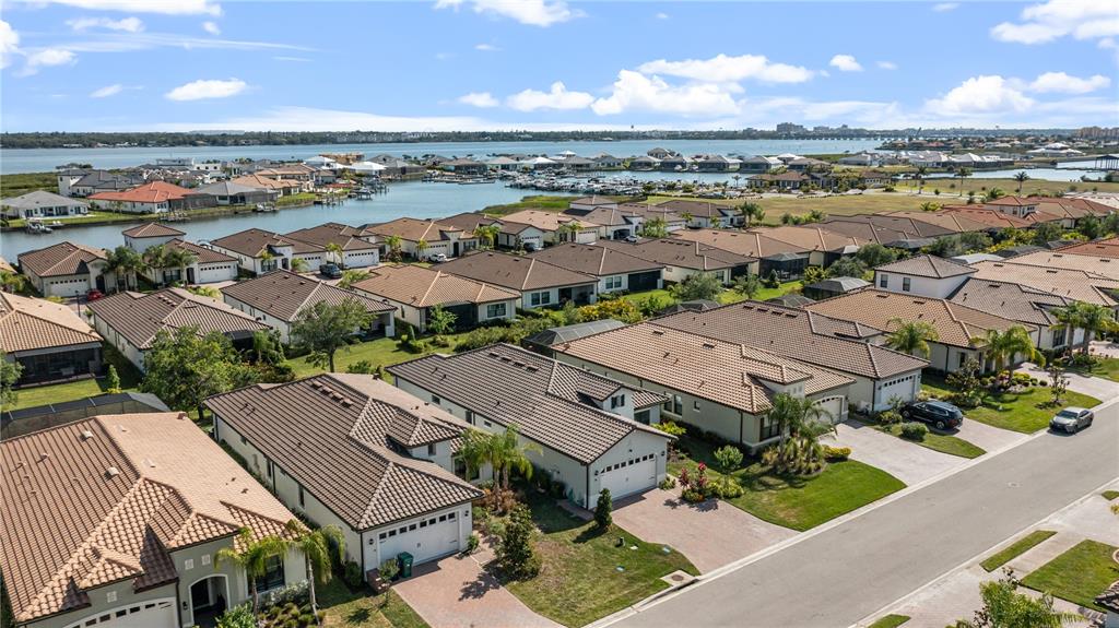 An aerial view shows a suburban neighborhood of houses with tile roofs near water — 2121 6TH STREET E, PALMETTO, FL