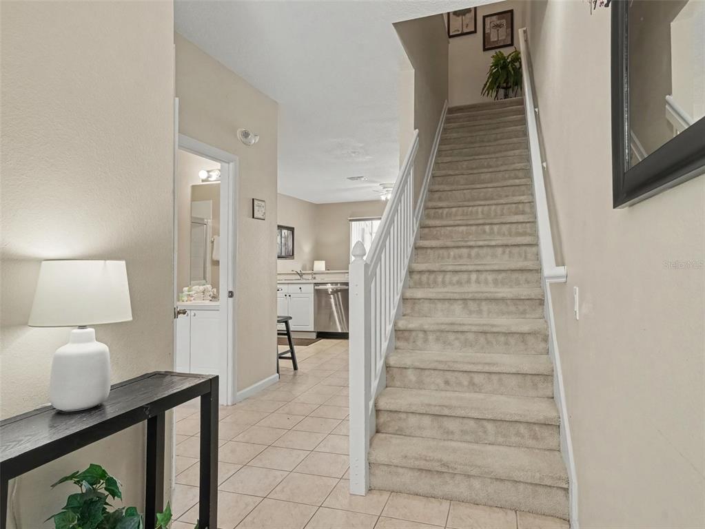 An entryway features a carpeted staircase, a tiled floor, and a view into the kitchen — 2326 SILVER PALM DR, KISSIMMEE, FL