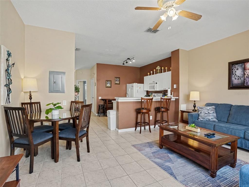 An open-concept living and dining area features tile flooring, a kitchen island, and neutral walls — 2326 SILVER PALM DR, KISSIMMEE, FL