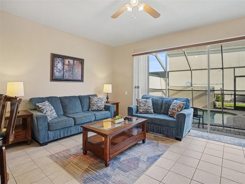 A living room features blue sofas, a wooden coffee table, and a sliding glass door — 2326 SILVER PALM DR, KISSIMMEE, FL