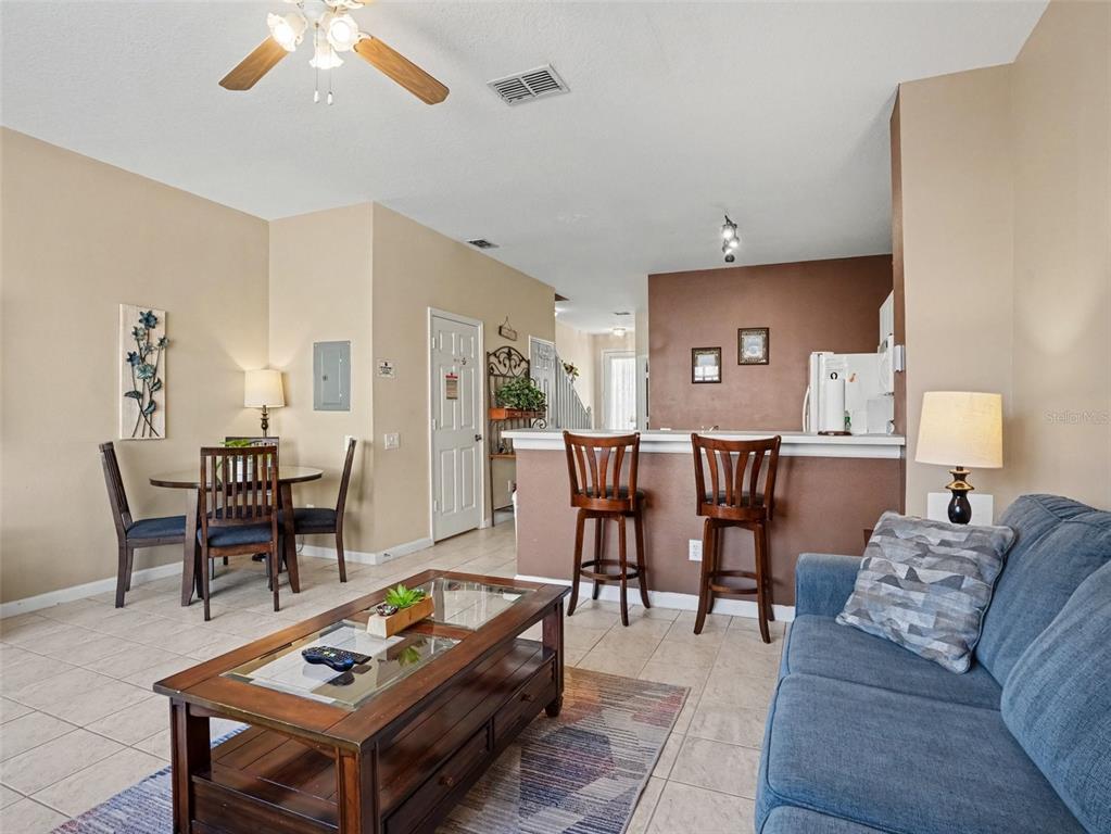 An open-concept living and dining area features tile flooring, a breakfast bar, and neutral walls — 2326 SILVER PALM DR, KISSIMMEE, FL