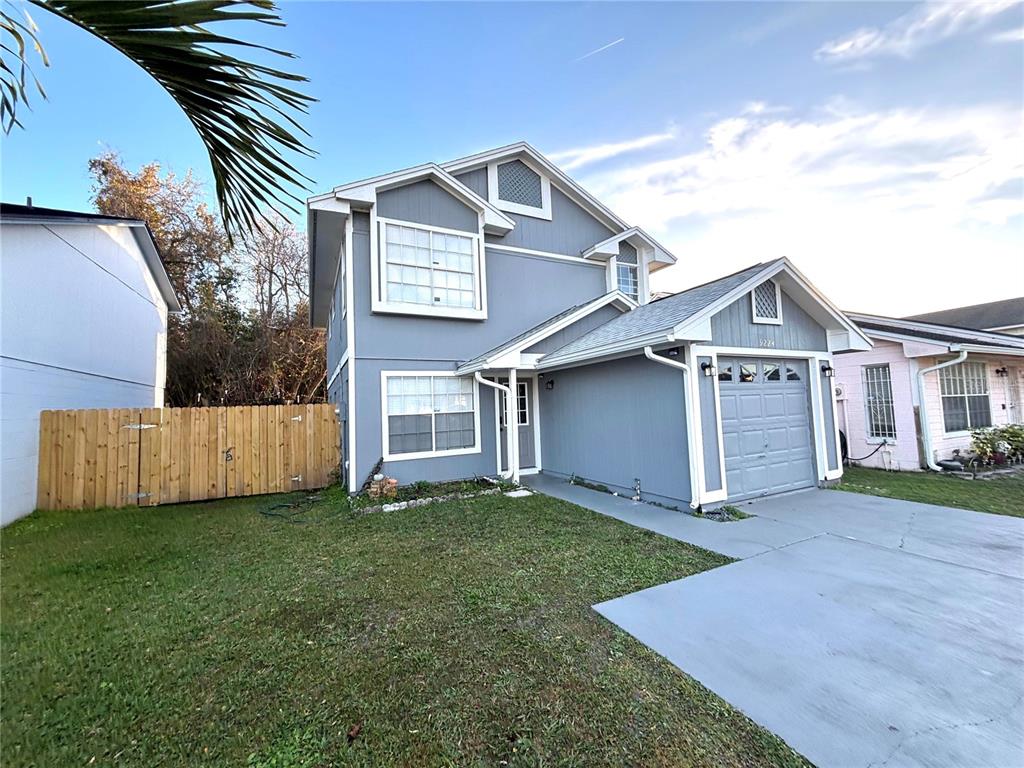 A two-story gray house with a single-car garage and a wooden fence on the side — 9224 VENTANA LANE, ORLANDO, FL
