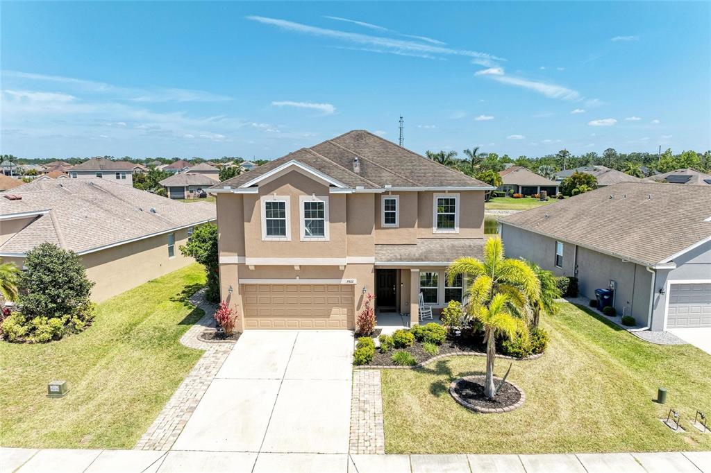 A two-story suburban house with a tan stucco exterior, a two-car garage, and a palm tree — 7822 110TH AVENUE E, PARRISH, FL