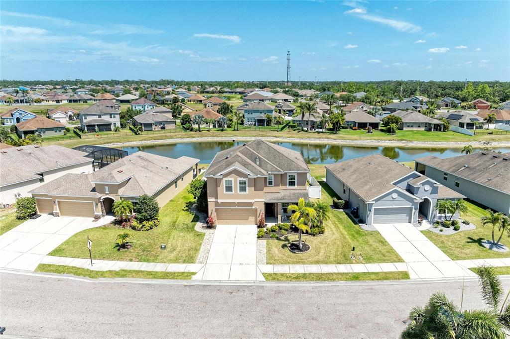 An aerial view shows a two-story suburban house with a pond in the backyard — 7822 110TH AVENUE E, PARRISH, FL