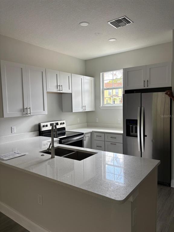 A modern kitchen features white cabinets, quartz countertops, stainless steel appliances, and a central island — 427 MADISON CIRCLE, DAVENPORT, FL