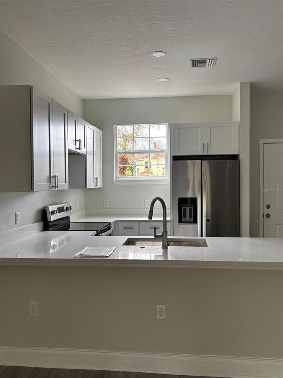 A kitchen features white cabinets, stainless steel appliances, a sink, and a breakfast bar — 427 MADISON CIRCLE, DAVENPORT, FL