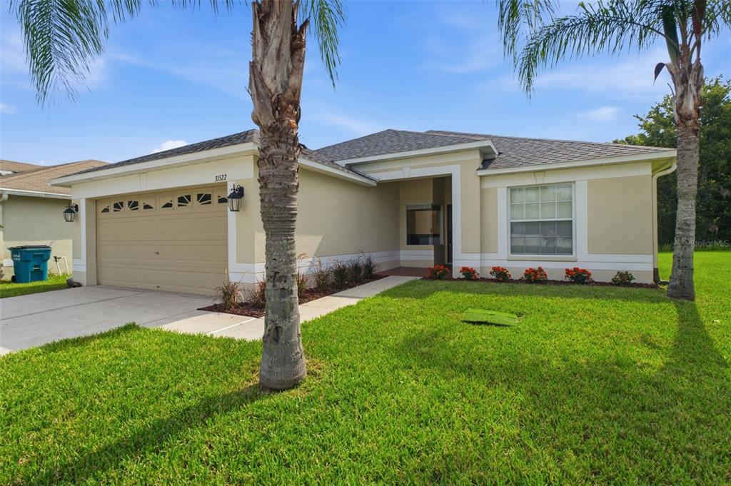 A kitchen features white cabinets, granite countertops, and a breakfast bar overlooking a dining area — 31522 TRIBOROUGH DRIVE, WESLEY CHAPEL, FL