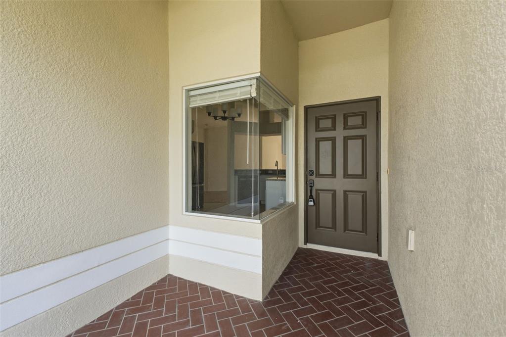 A hallway with light wood-look flooring leads toward a living area with a sliding door — 31522 TRIBOROUGH DRIVE, WESLEY CHAPEL, FL