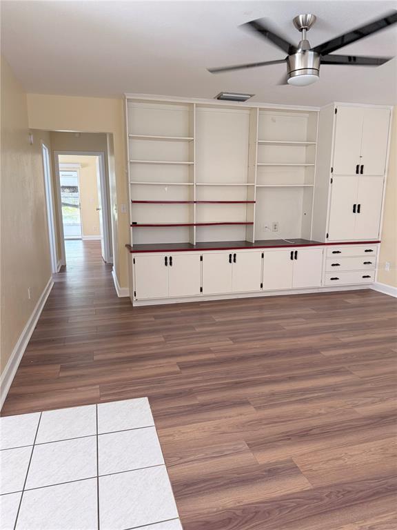 A living room features wood-look flooring, a ceiling fan, and a large built-in wall unit — 402 DORCHESTER PLACE UNIT 44, SUN CITY CENTER, FL