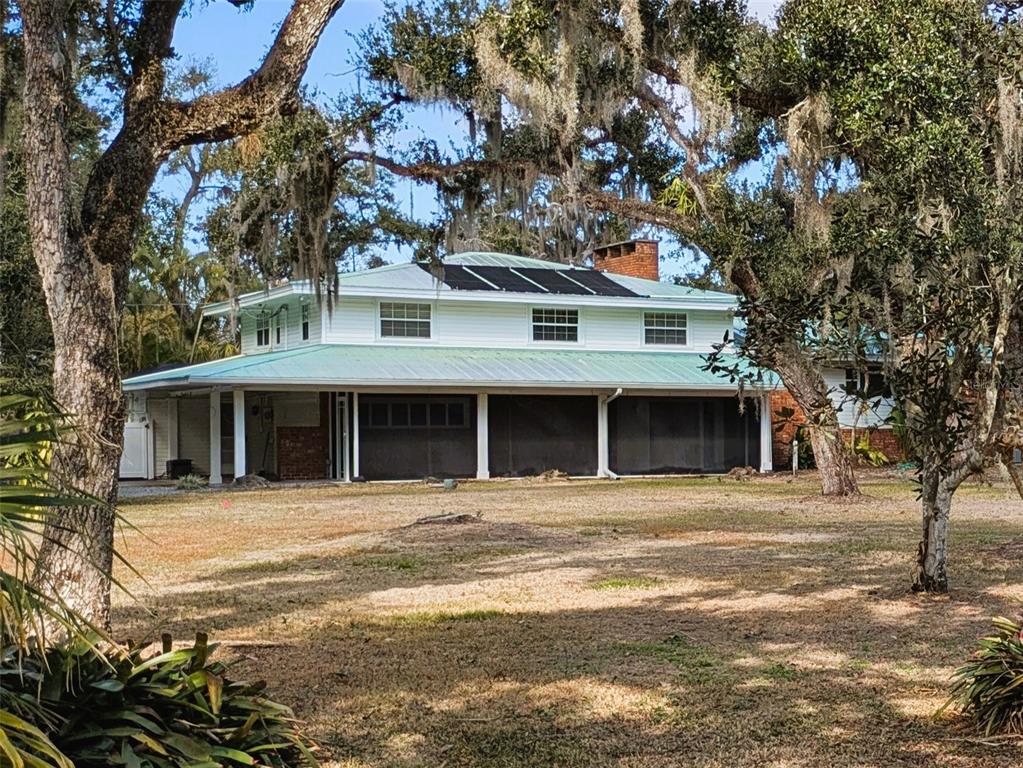 A two-story house with a metal roof, solar panels, and a large screened-in porch — 4554 COOPER ROAD, SARASOTA, FL