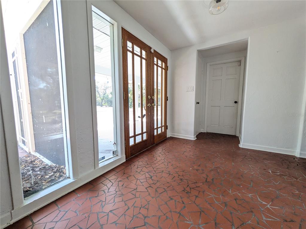 An entryway features a red tile floor, double wooden doors, and a white interior door — 4554 COOPER ROAD, SARASOTA, FL