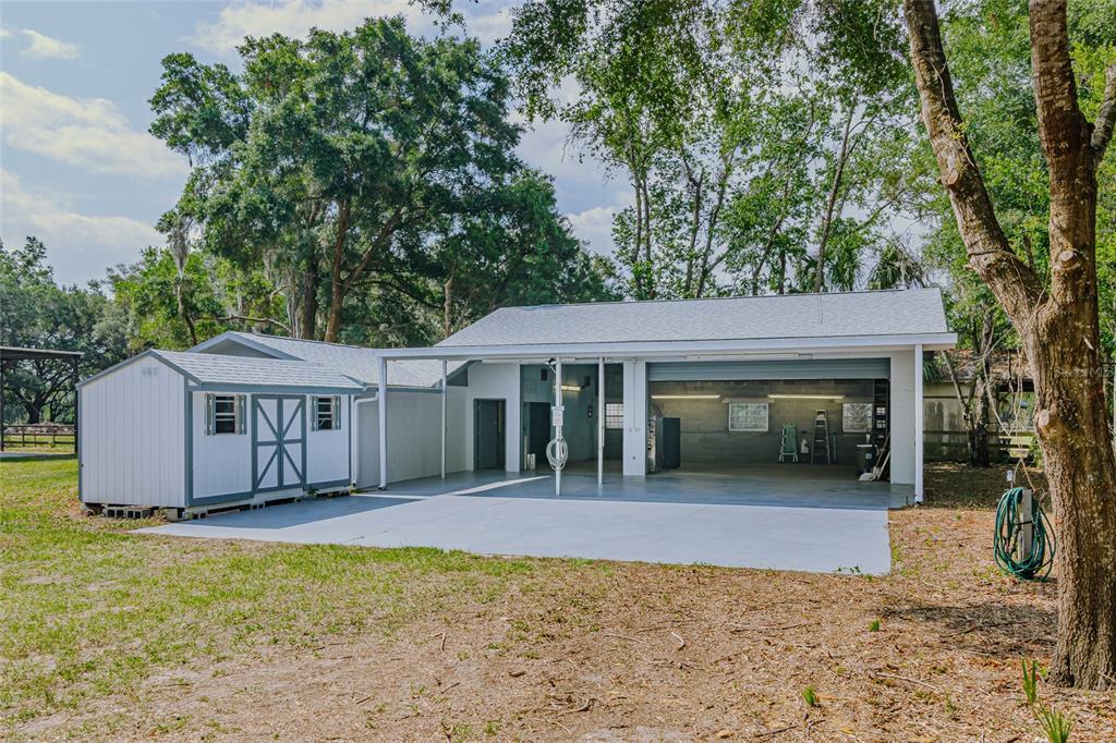 A detached garage with an attached storage shed and a large concrete patio area — 6875 NE 25TH AVENUE, OCALA, FL