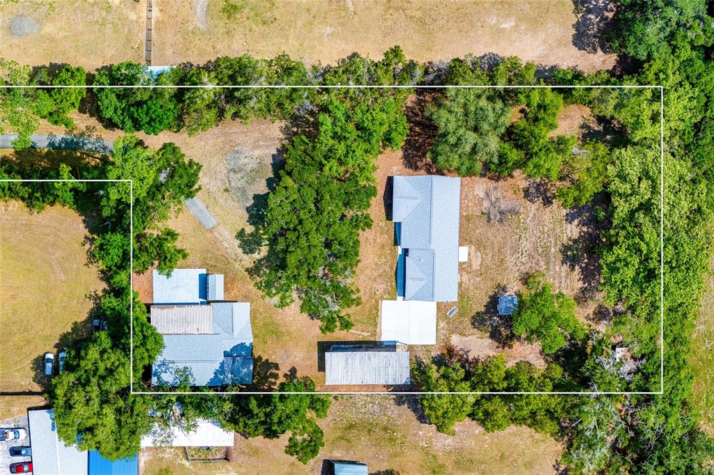 An aerial view shows a rural property with multiple buildings, trees, and open land — 6875 NE 25TH AVENUE, OCALA, FL