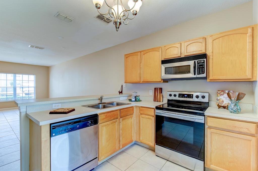 An empty room with beige tile flooring, light walls, and a small bathroom entrance — 509 WILTON CIRCLE, SANFORD, FL