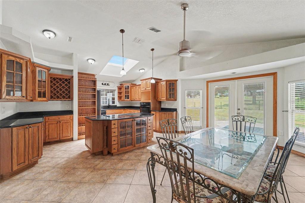 A kitchen with wood cabinets, a center island, and a dining area with glass doors — 6446 LUCKY LANE, SPRING HILL, FL