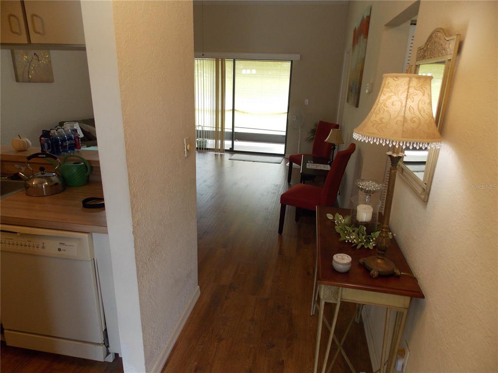 A kitchen with a dishwasher and a living area with wood-look flooring and sliding glass doors — 26267 NORTHERN CROSS ROAD UNIT 6C, PUNTA GORDA, FL