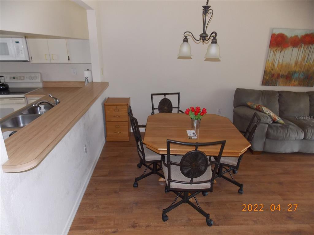A dining area with a wooden table and chairs sits adjacent to a kitchen counter — 26267 NORTHERN CROSS ROAD UNIT 6C, PUNTA GORDA, FL