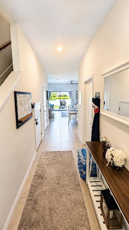 A hallway with tile floors, a runner rug, and a console table leads toward a patio — 5698 ARCHIPELAGO STREET, NOKOMIS, FL