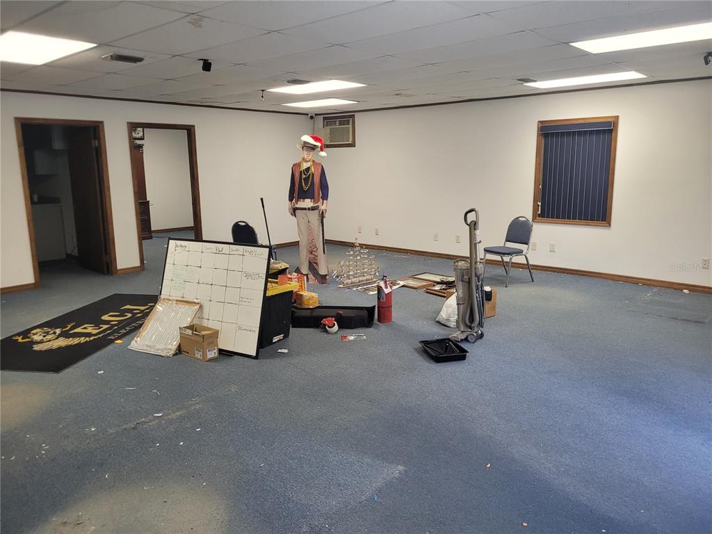 An empty office room with blue carpeting, a whiteboard, and a cardboard cutout figure — 8875 E HIGHWAY 25, BELLEVIEW, FL