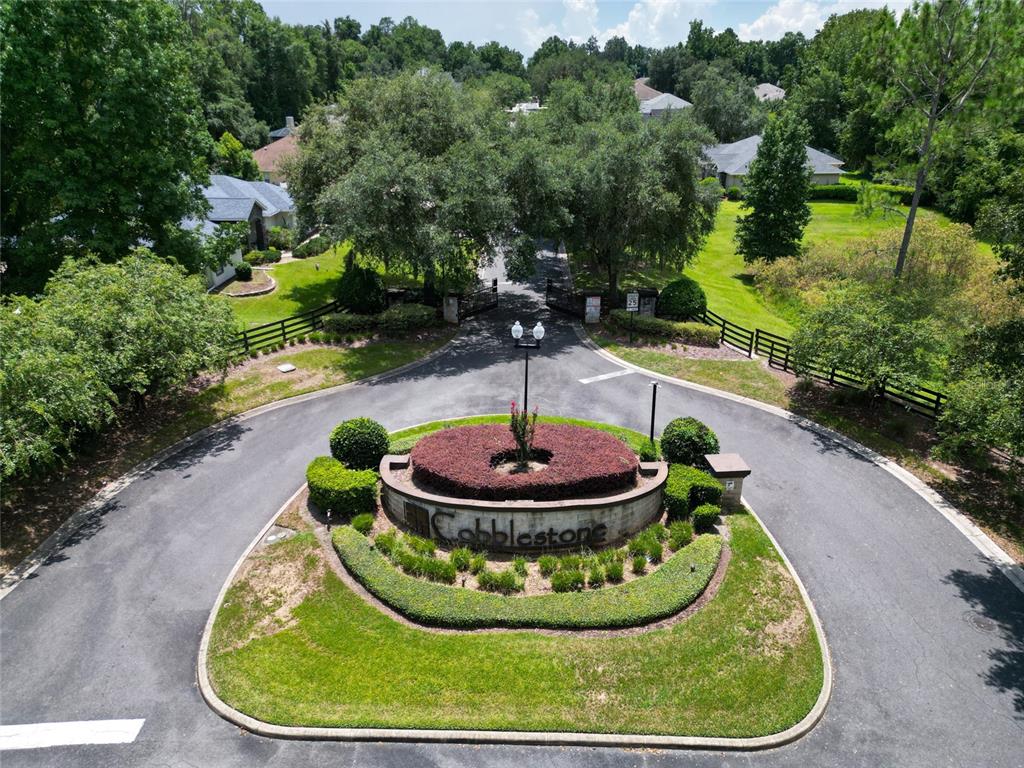 An aerial view shows the gated entrance to a residential community with a landscaped island — 10040 SE 42ND COURT, BELLEVIEW, FL