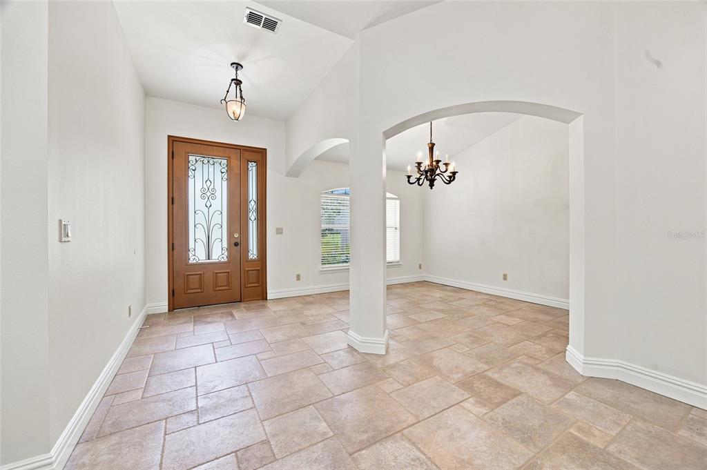 An entryway with tile flooring, a wooden front door, and an arched opening to a room — 10040 SE 42ND COURT, BELLEVIEW, FL