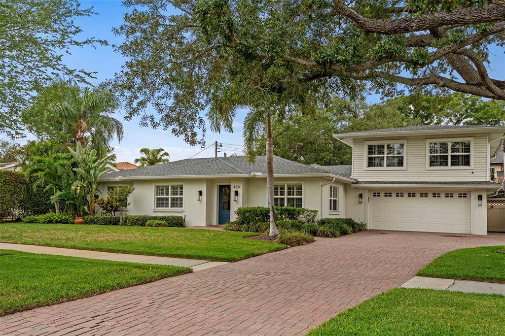 A two-story house with light-colored siding, a brick driveway, and a palm tree in front — 480 W DAVIS BOULEVARD, TAMPA, FL