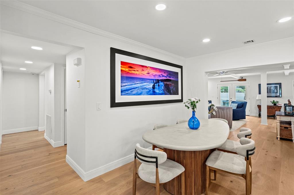 A modern white kitchen features a large island with bar stools and light wood flooring — 480 W DAVIS BOULEVARD, TAMPA, FL