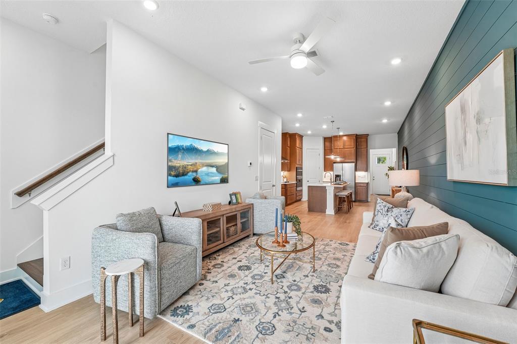 A living room with a blue shiplap wall, a white sofa, and an open kitchen — 14995 CATTERICK COURT, JACKSONVILLE, FL