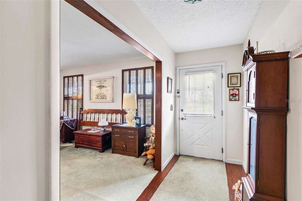An entryway with a grandfather clock leads into a carpeted living area with wooden furniture — 7797 132ND WAY, SEMINOLE, FL