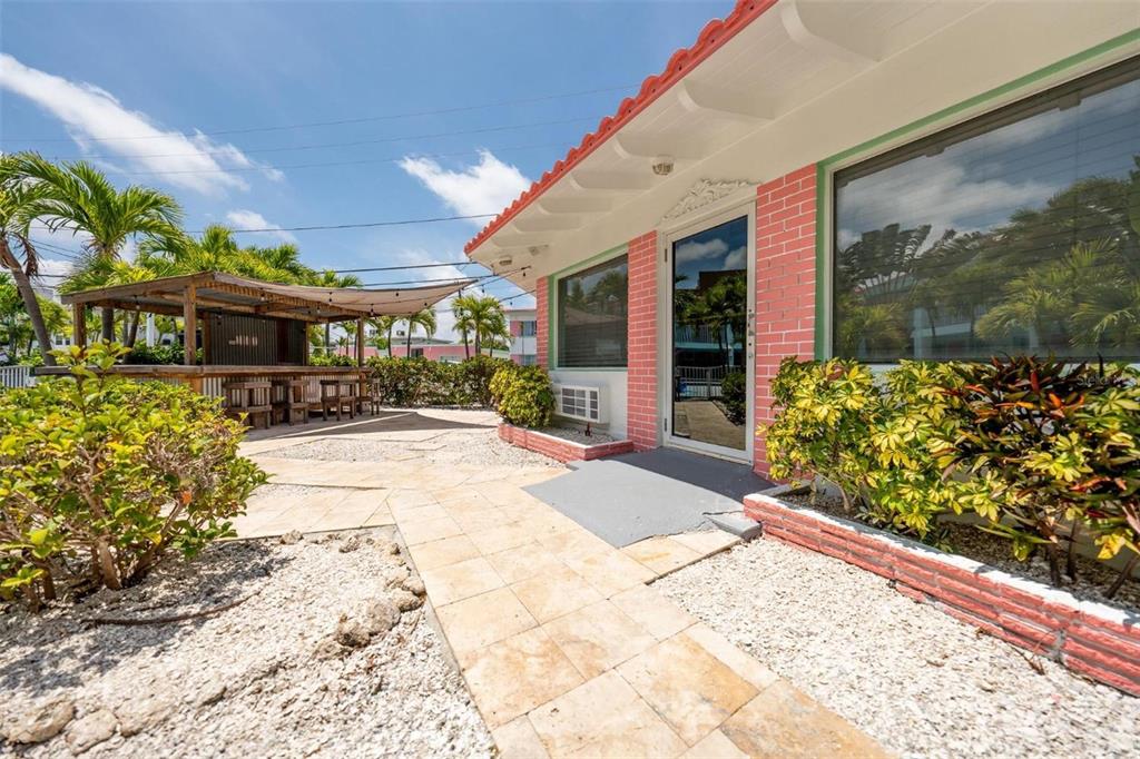 A pink brick building exterior features a tiled walkway, a glass door, and a tiki bar — 333 HAMDEN DRIVE, CLEARWATER BEACH, FL