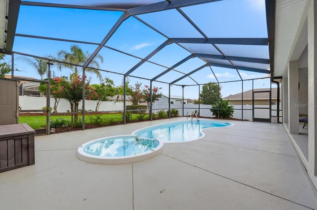 A screened-in patio features a kidney-shaped swimming pool and a separate circular spa — 5618 SUMMERLAND HILLS DRIVE, LAKELAND, FL