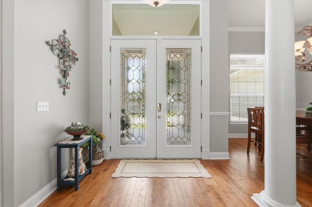 An entryway features double glass-paneled doors, hardwood floors, and a decorative wall cross — 5618 SUMMERLAND HILLS DRIVE, LAKELAND, FL