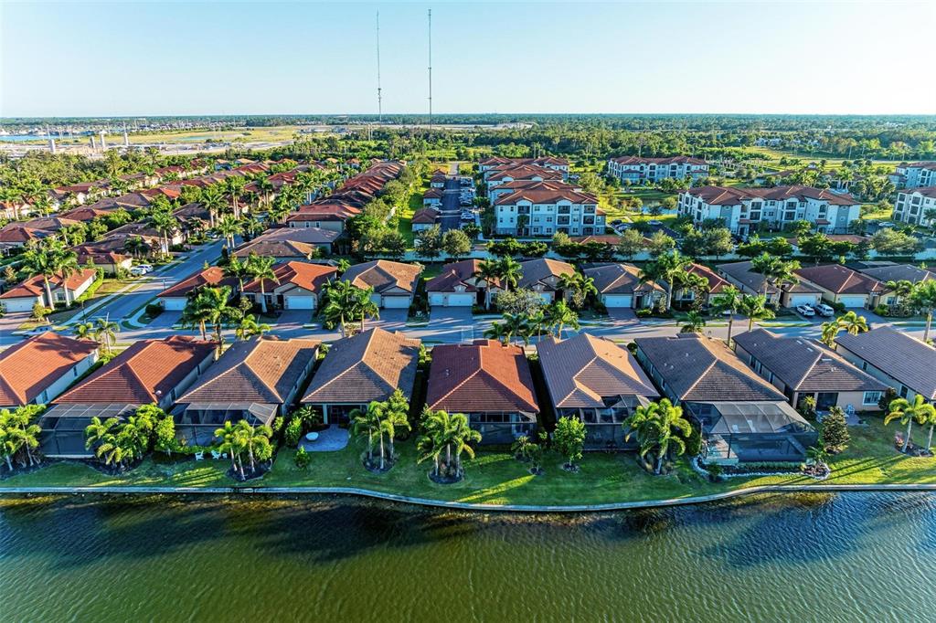 An aerial view of a suburban neighborhood featuring houses with tiled roofs along a lake — 228 MARAVIYA BOULEVARD, NOKOMIS, FL