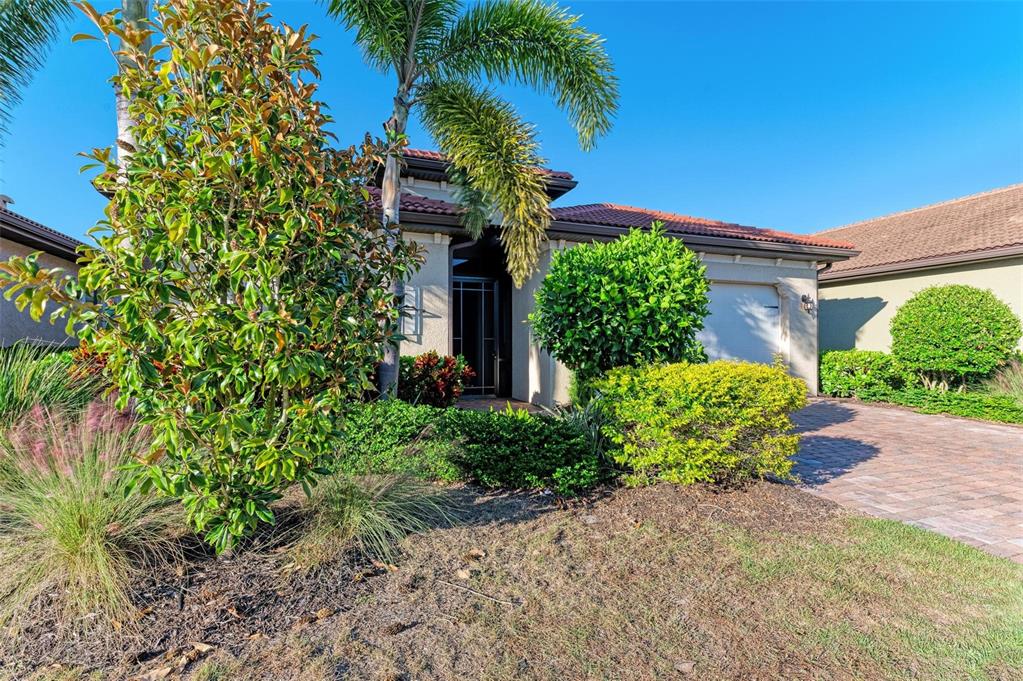A single-story house with a tiled roof, a paved driveway, and lush landscaping — 228 MARAVIYA BOULEVARD, NOKOMIS, FL