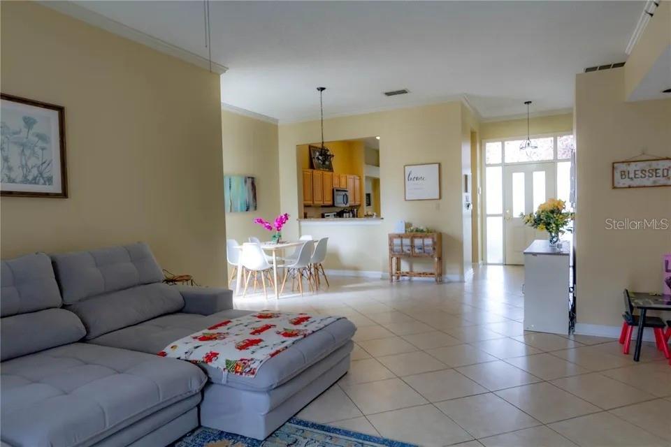 A living room with a gray sectional sofa opens to a dining area and kitchen — 2545 CLARINET DRIVE, ORLANDO, FL