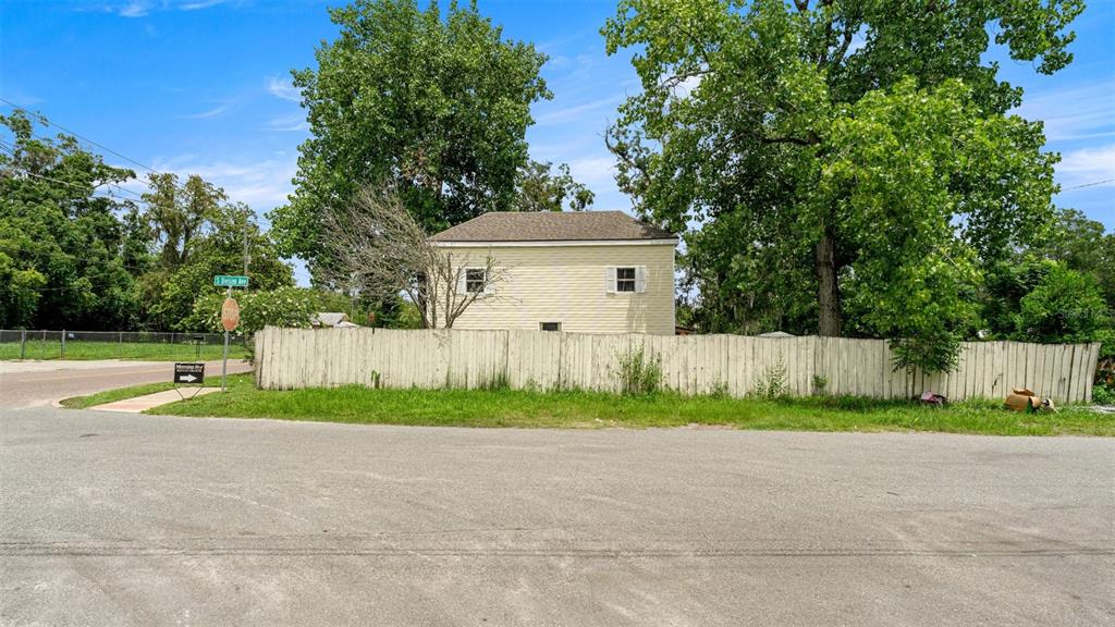 A yellow two-story house stands behind a weathered white wooden fence near a street corner — 10107 S DIVISION AVENUE, HAMPTON, FL