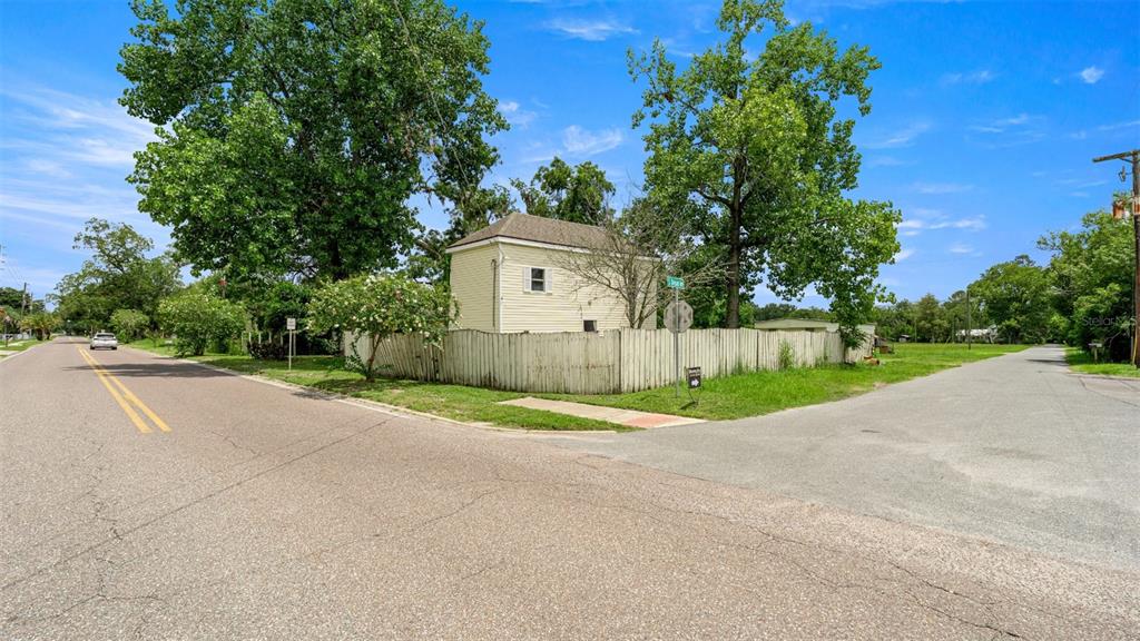A yellow house with a wooden fence sits at the corner of two paved roads — 10107 S DIVISION AVENUE, HAMPTON, FL