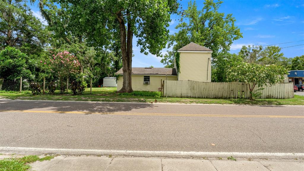 A yellow house with a tall tower section sits behind a wooden fence and trees — 10107 S DIVISION AVENUE, HAMPTON, FL
